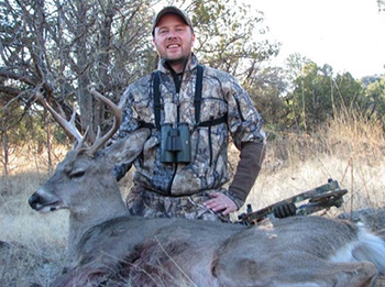 A man standing next to a dead deer.
