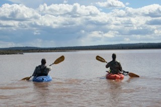 Two people in kayaks paddling through a lake.